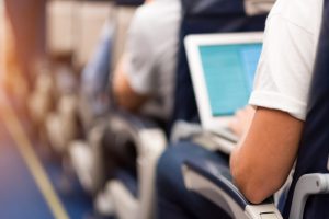 Man typing on a laptop aboard the plane