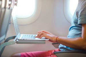 Man Sitting in the Airplane and Working on his Laptop