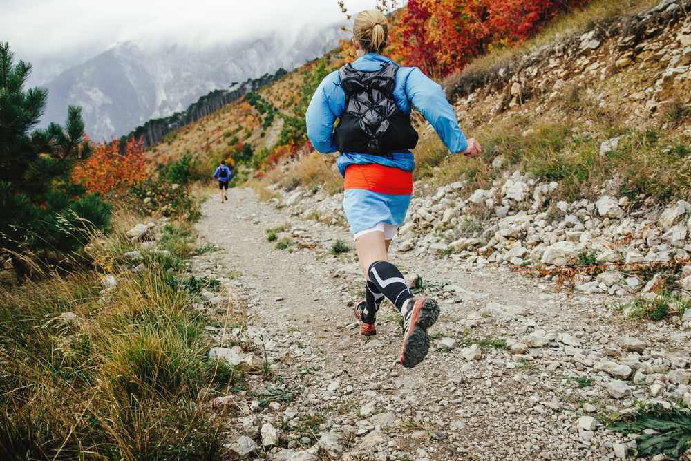 female athlete runner running mountain marathon with backpack