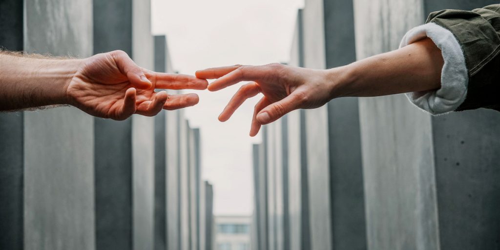 two hands reaching to each other across gray background