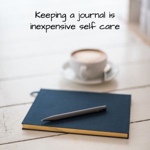 Close journal, pen, and coffee cup on a table.