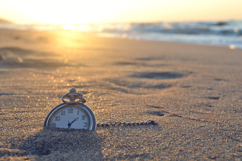 Old-fashioned watch buried in sand at the beach