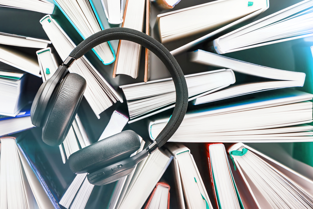 Wireless overhead black headphones lie on a bunch of books.