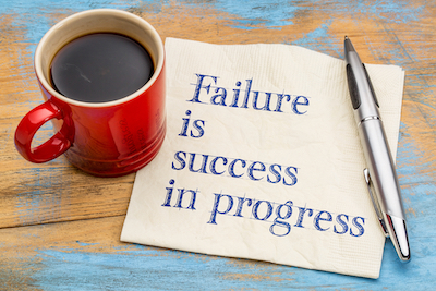 Failure is success in progress - handwriting on a napkin with a cup of coffee