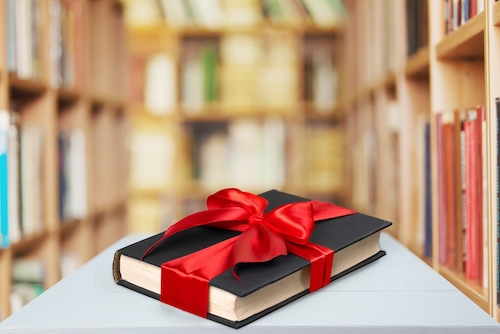 A book with a red bow, with bookstore shelves in the background