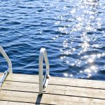 Dock and ladder on calm summer lake with sparkling water