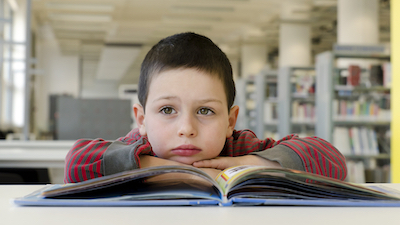 child daydreaming while reading a book