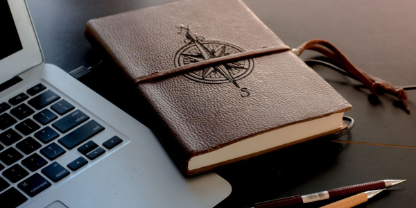 laptop, diary with compass image on the front