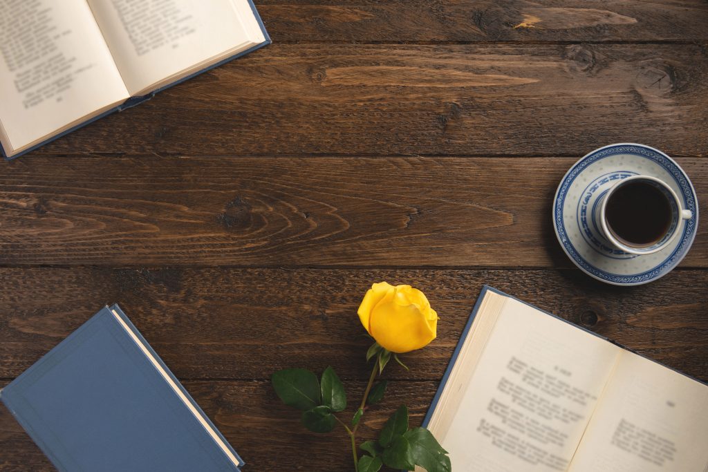 wooden desktop with book of poems, coffee, rose